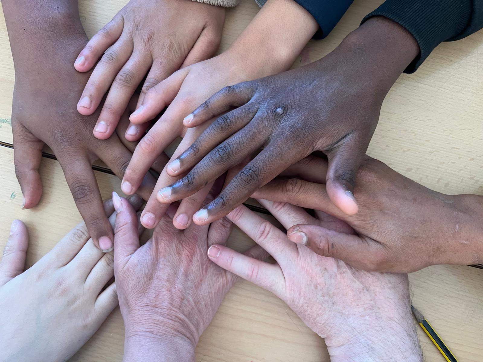 Imagen donde se pueden ver manos de diferentes etnias representando la multiculturalidad como uno de los valores del centro